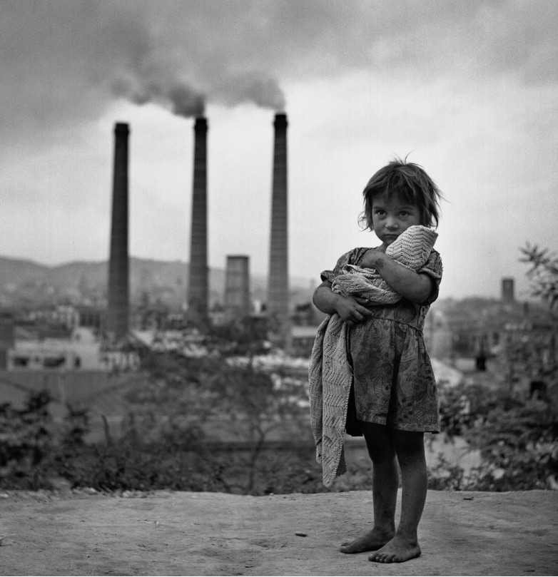 Fotografia di una bambina davanti alle fabbriche di Barcellona